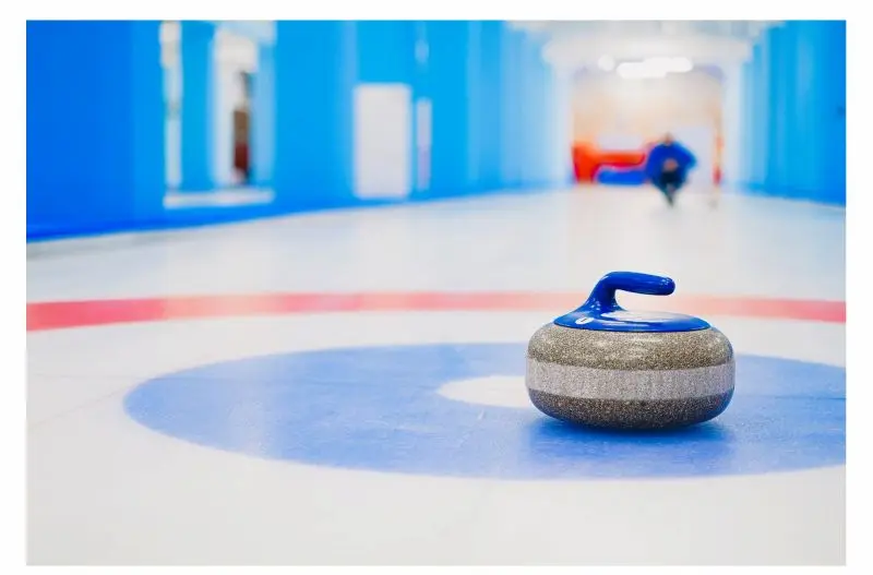 Curling Stone on the Ice Curling stone positioned on the blue target area of an ice sheet