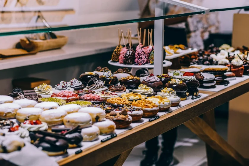 Bakery case filled with colorful donuts, cupcakes, and candy apples on sticks.