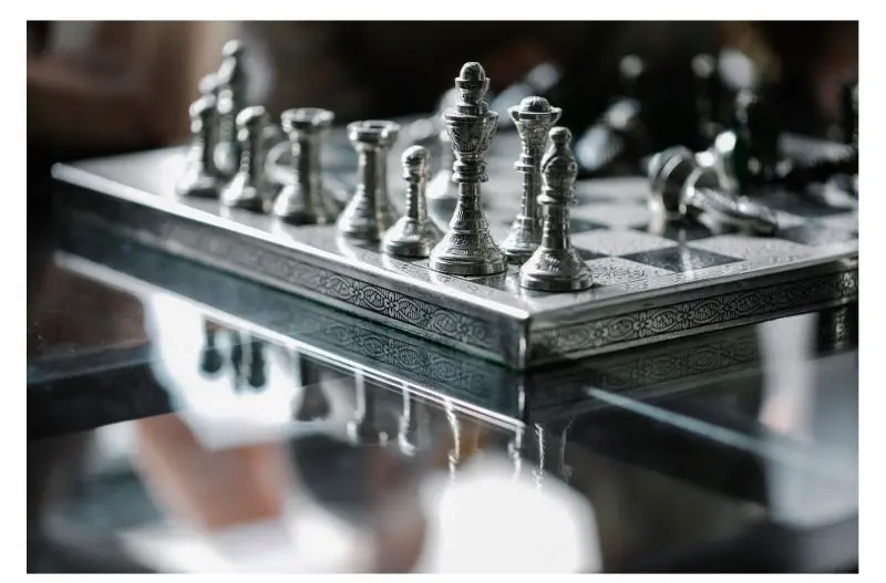 The Art of the Chessboard Silver chess pieces standing on an intricately patterned board